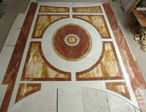 Pavimento decorato con piastrelle circolari nei toni del marrone, crema e oro.