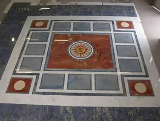 Piastrella decorativa geometrica per pavimento con motivo centrale a fiore arancione e quadrati di bordo grigi.