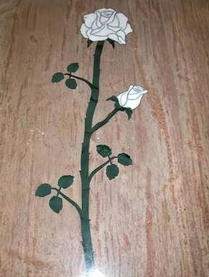 Stelo di rosa bianca con foglie verdi su sfondo di legno.