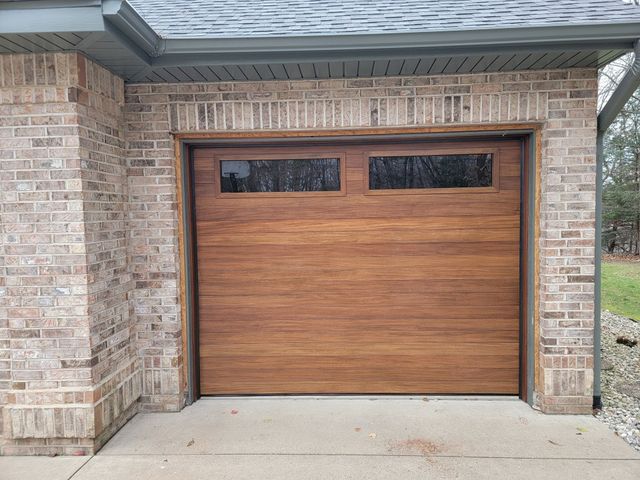 Wooden single garage door set in a brick exterior with a concrete driveway.