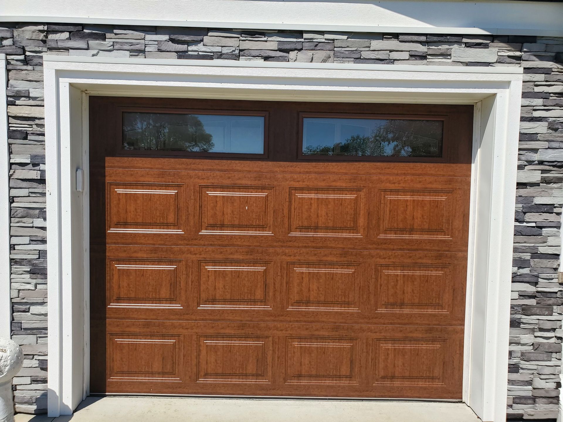 Wooden garage door with upper windows set in a stone exterior facade