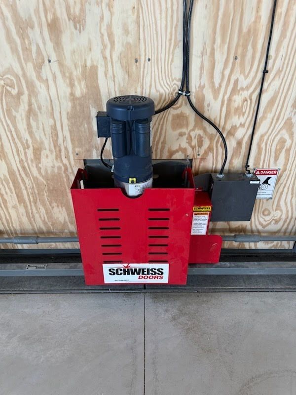 Red Schmersal machine unit mounted on a plywood wall beside a gray control box.