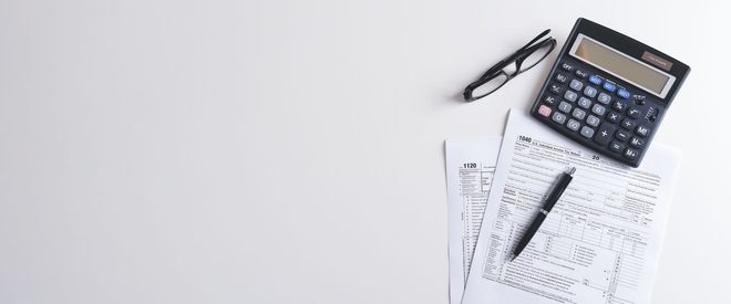 Calculator, pen, and paperwork on a white desk Calculator, pen, and paperwork on a white desk