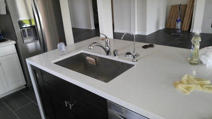 Granite countertop with stainless sink, chrome-plated lead-free RO drinking-water faucet, and a separate chrome air-gap device mounted on the counter.