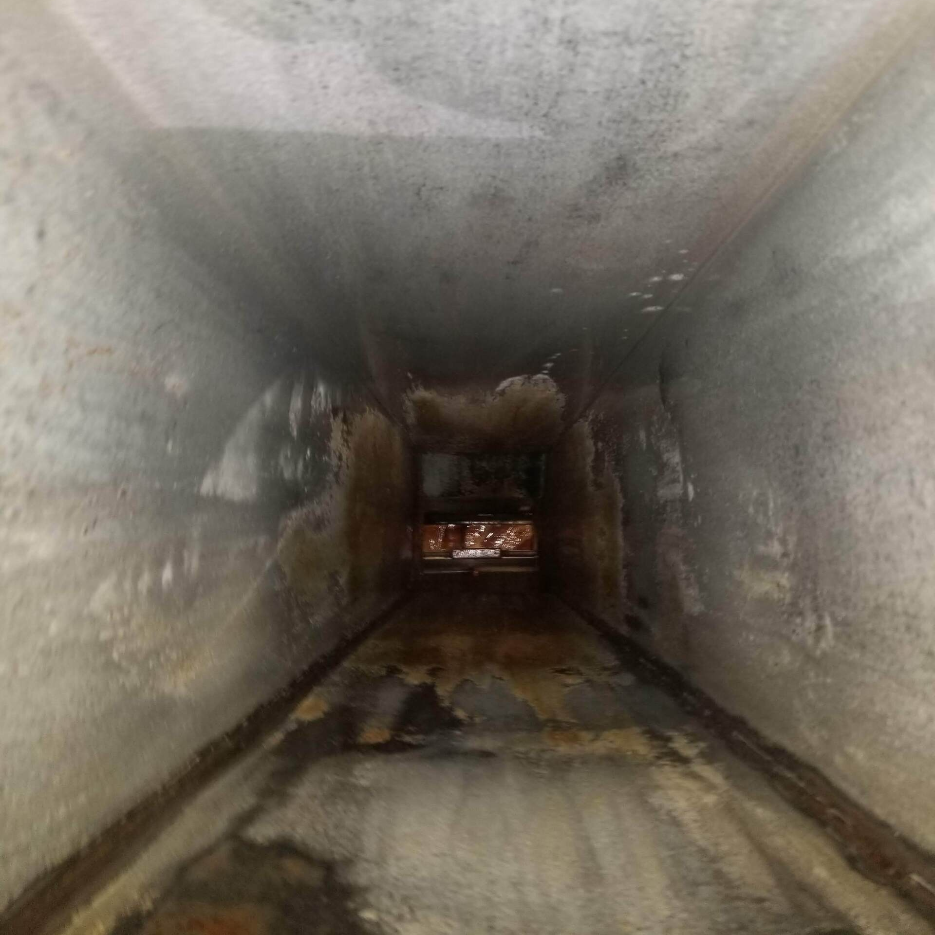 a long narrow tunnel with a concrete floor and walls .
