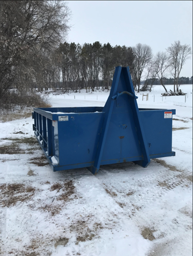 Blue dumpster at a snowy site.
