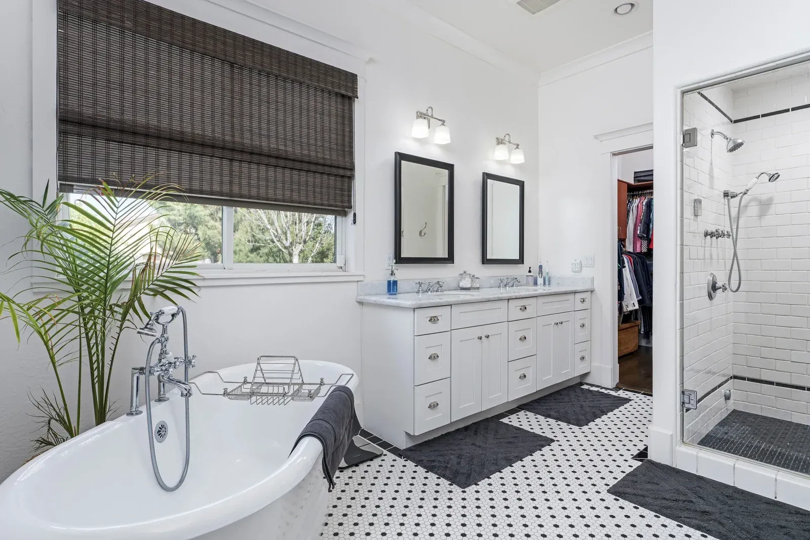 White bathroom with soaking tub, vanity, shower, and patterned tile floor.