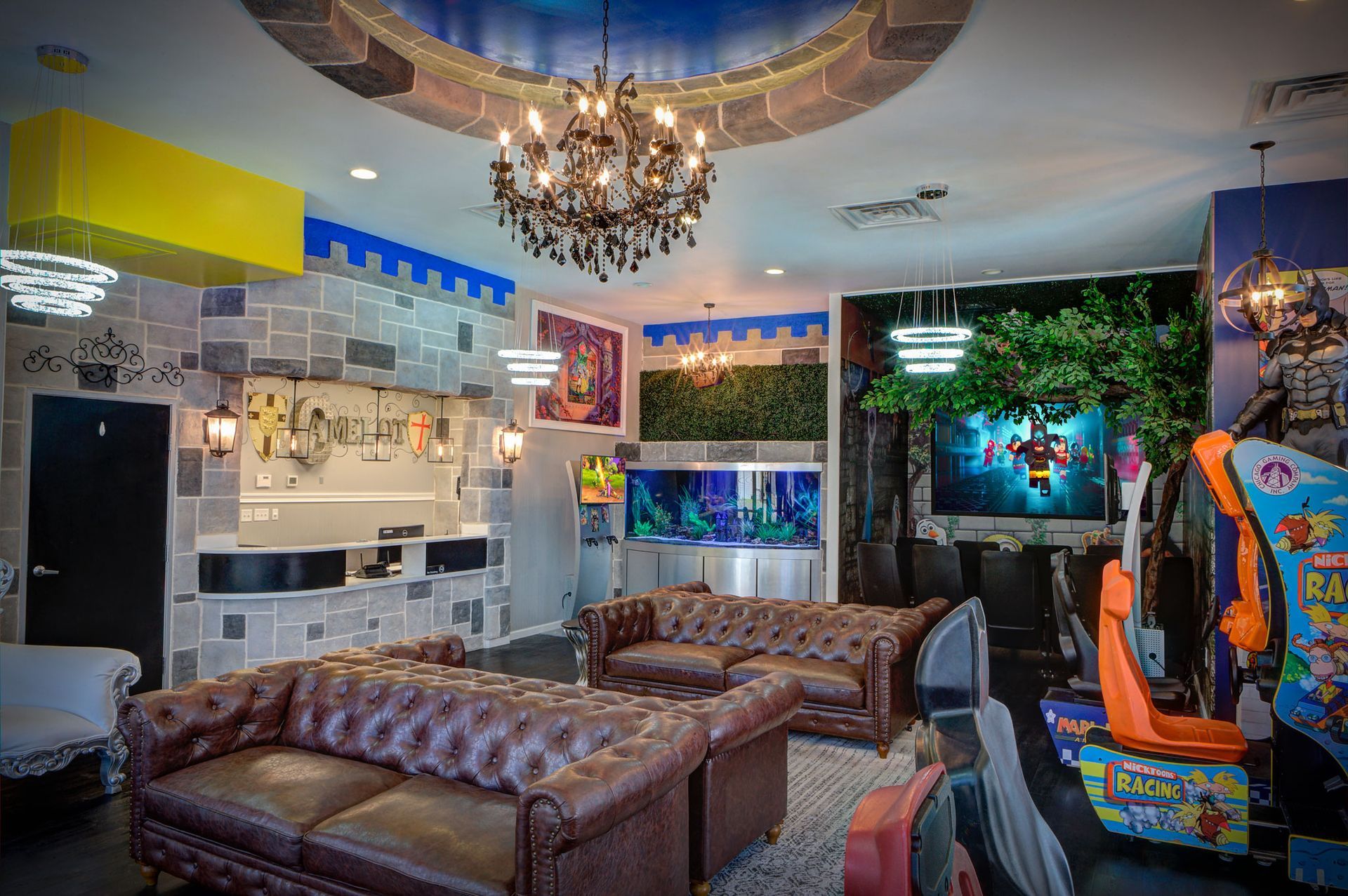 Eclectic living room with tufted leather sofas, chandeliers, colorful wall art, and aquarium-style displays