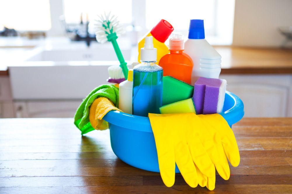 A Blue Bowl Filled with Cleaning Supplies on A Wooden Table — Haydyn's Cleaning In Eli Waters, QLD