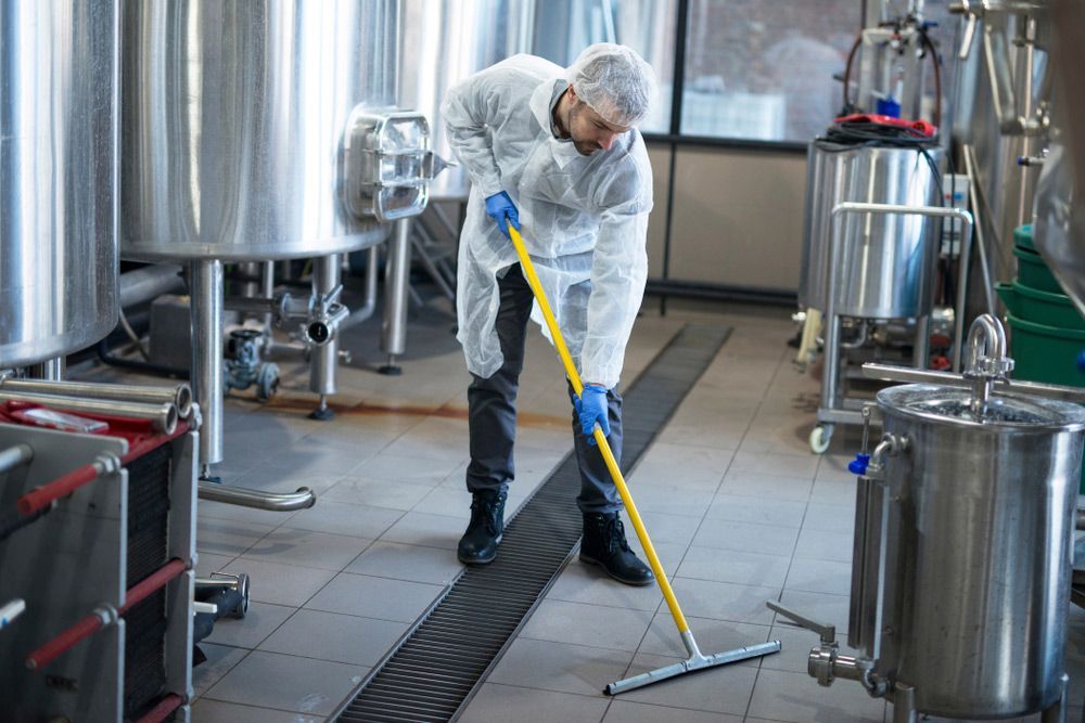 A Man Is Cleaning the Floor of A Factory with A Mop — Haydyn's Cleaning In Eli Waters, QLD