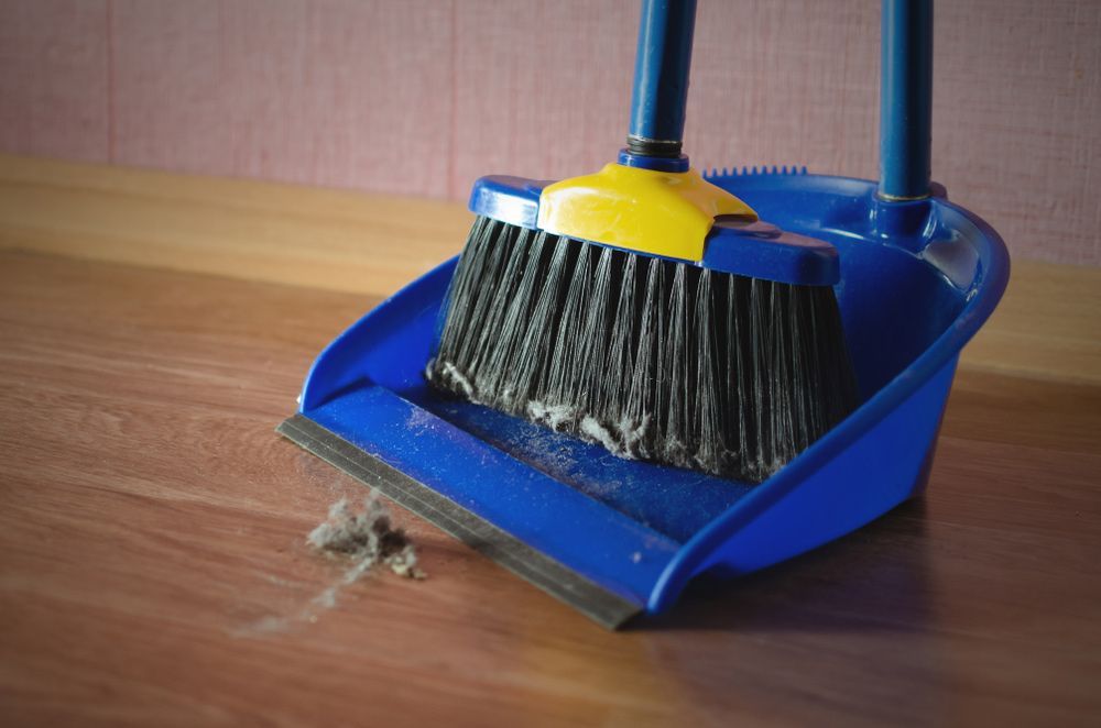A Broom and Dustpan Are Sitting on A Wooden Floor — Haydyn's Cleaning In Urraween, QLD
