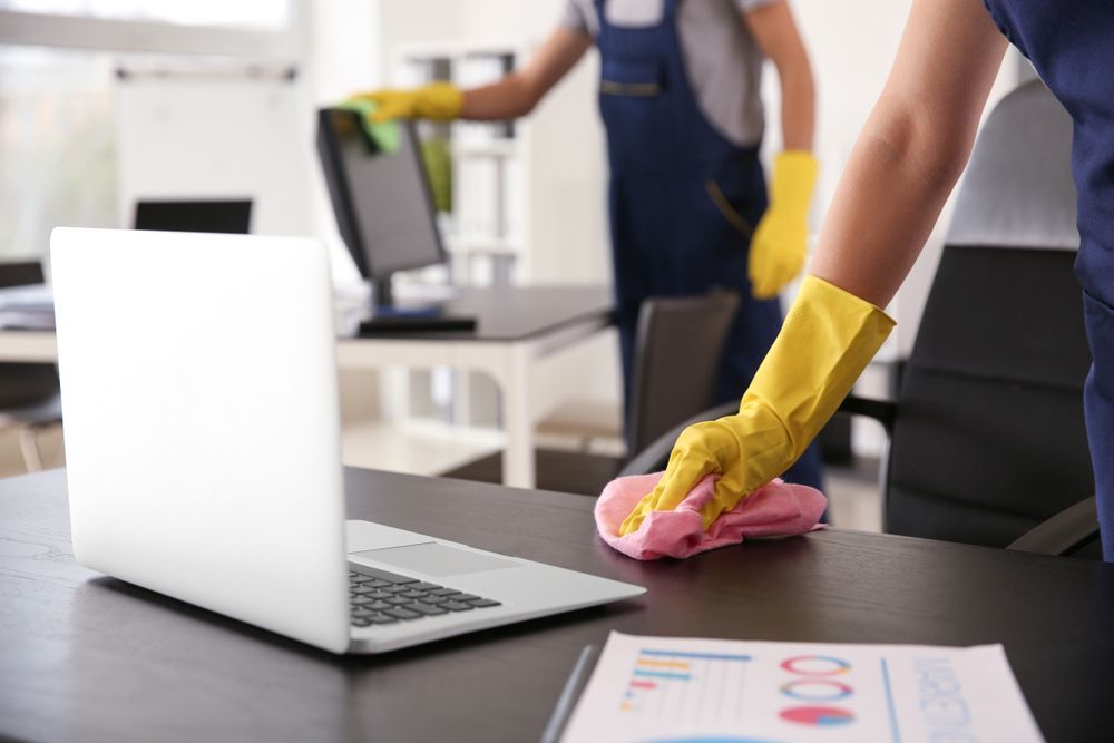 A Person Is Cleaning a Desk with A Cloth in An Office — Haydyn's Cleaning In Kawungan, QLD