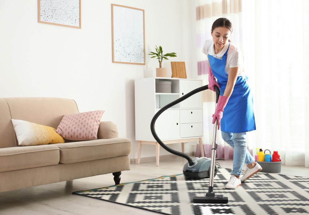 A Woman Is Using a Vacuum Cleaner to Clean a Rug in A Living Room — Haydyn's Cleaning In Kawungan, QLD