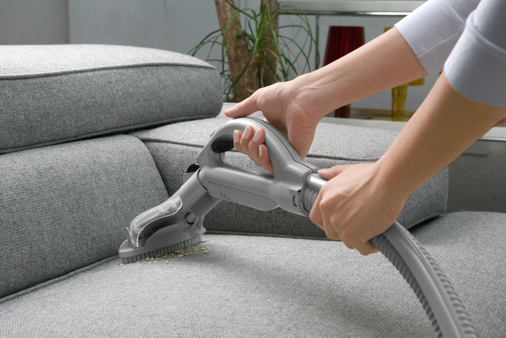 A Person Is Cleaning a Couch with A Vacuum Cleaner — Haydyn's Cleaning In Kawungan, QLD
