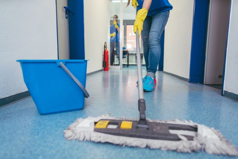 A Woman Is Cleaning a Hallway with A Mop and Bucket — Haydyn's Cleaning In Point Vernon, QLD