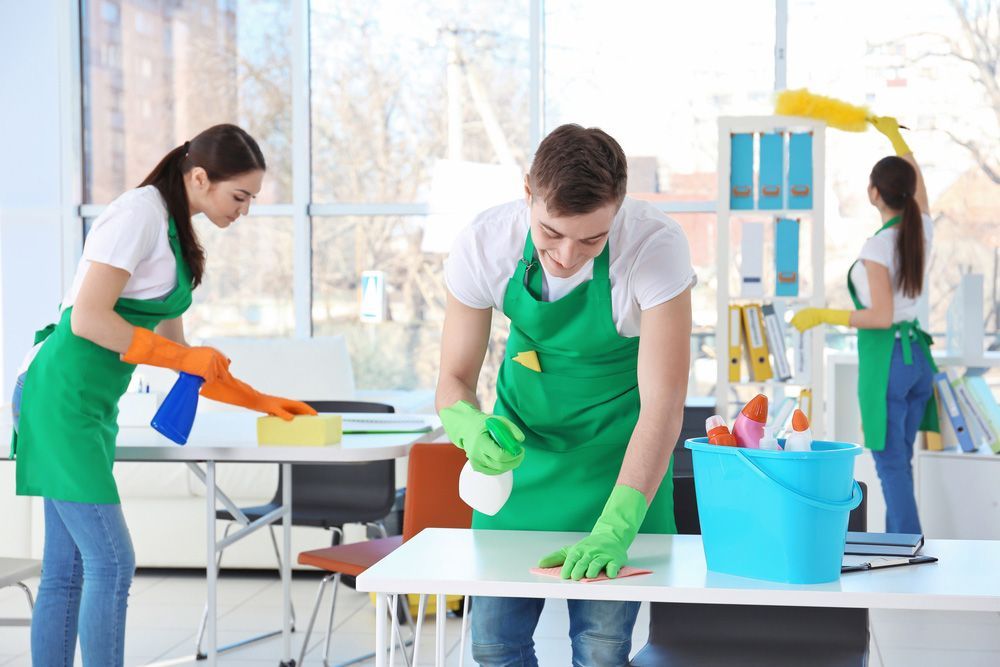 A Group of People Are Cleaning a Table in An Office — Haydyn's Cleaning In Torquay, QLD