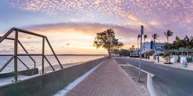 A Brick Walkway Next To A Body Of Water At Sunset — Haydyn's Cleaning In Urangan, QLD