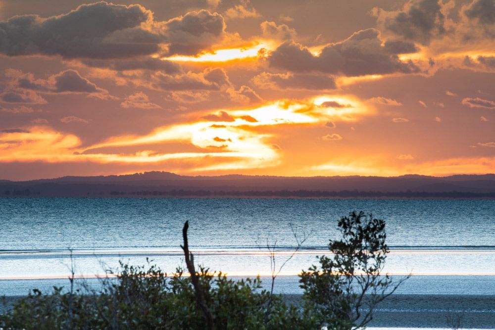A Sunset Over A Body Of Water With Trees In The Foreground — Haydyn's Cleaning In Pialba, QLD