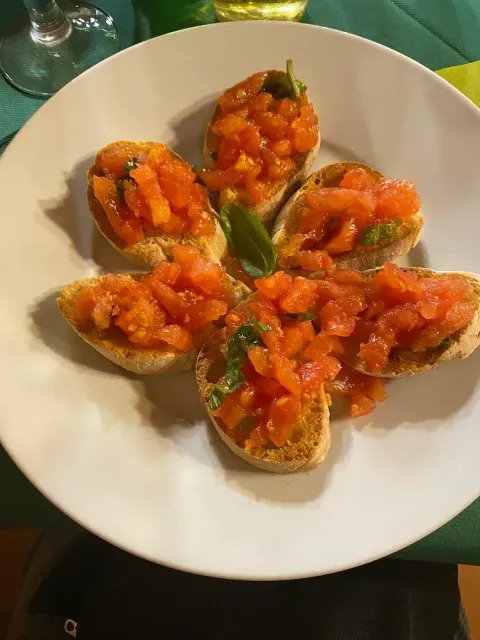 Sei tortillas a forma di cestello, guarnite con pomodori a cubetti e disposte su un piatto bianco a mo' di fiore.