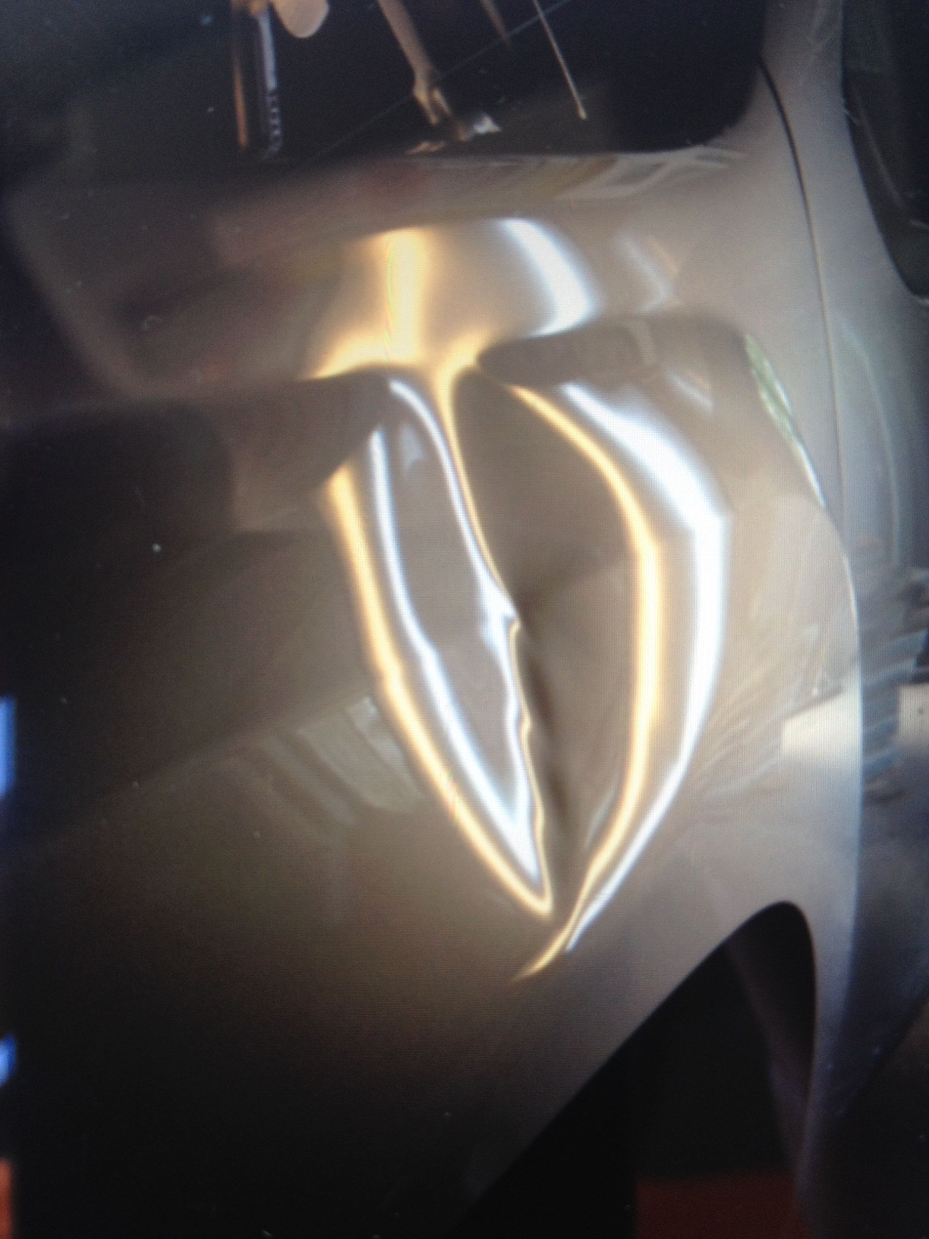 A close up of a car with a dent in the fender