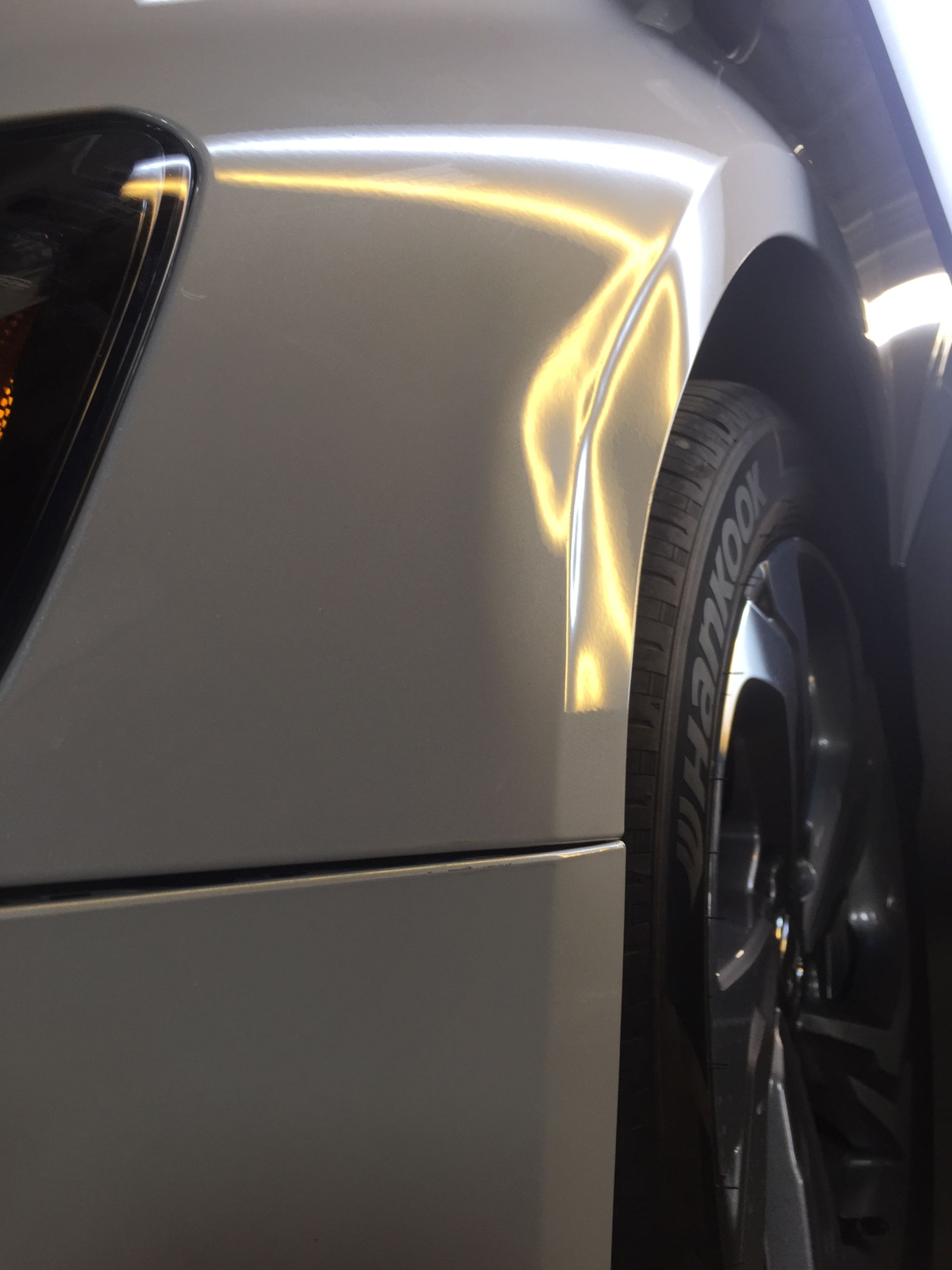 A close up of a white car with a tire that says pirelli