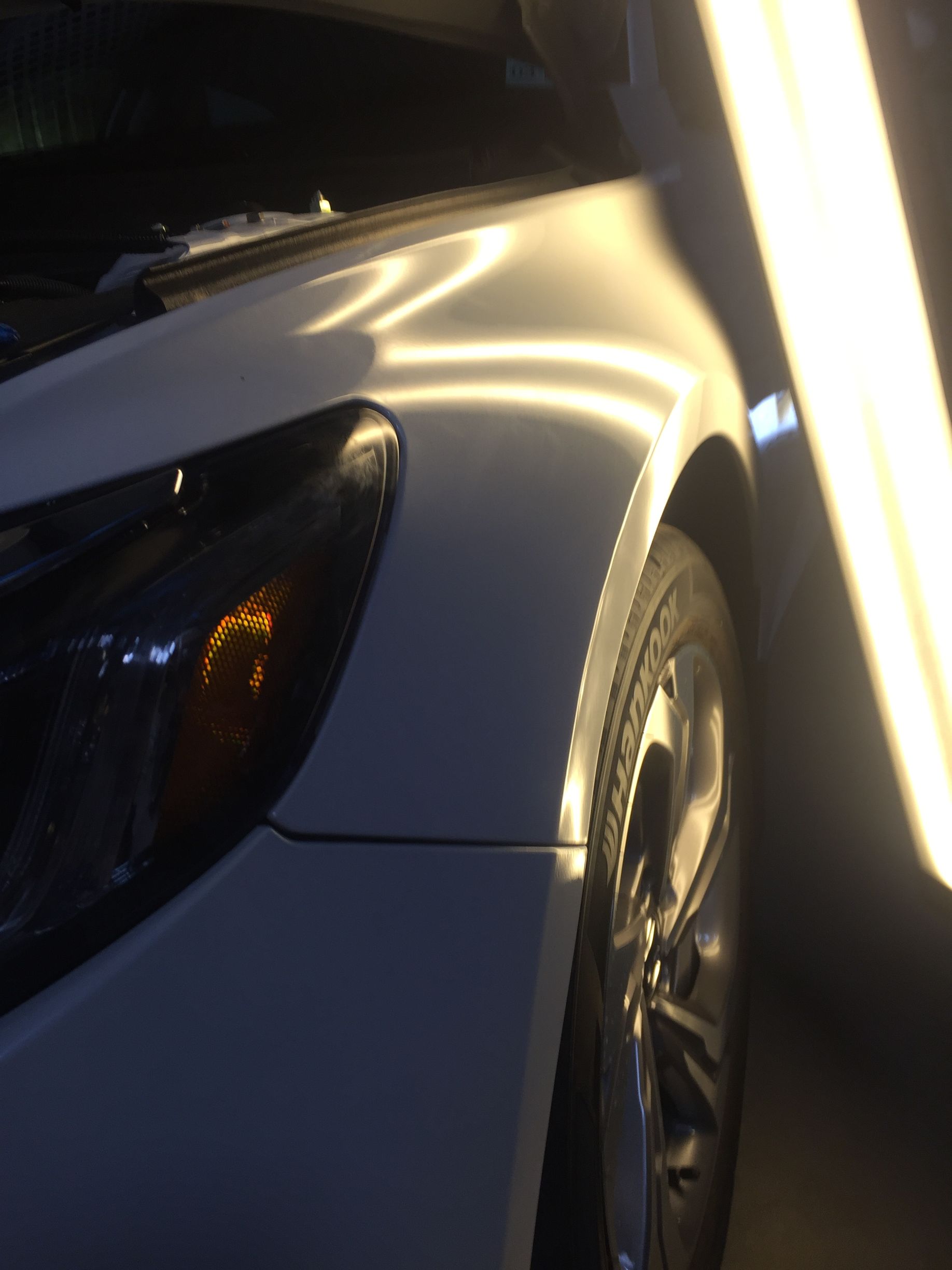 A close up of a white car with a light shining on it