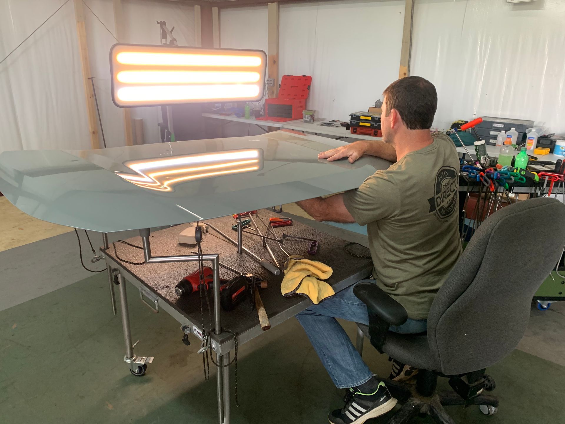 A man is sitting at a table working on a piece of glass.