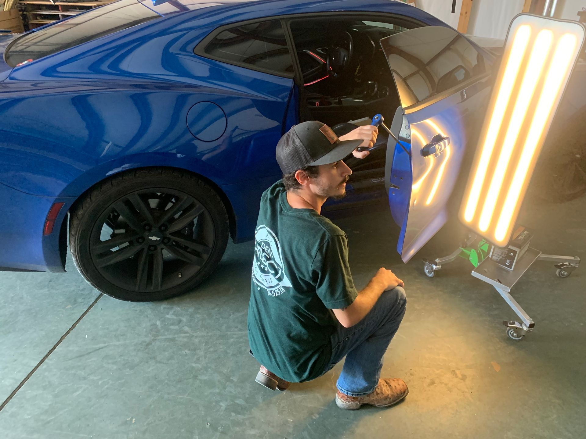 A man is working on a blue car in a garage.