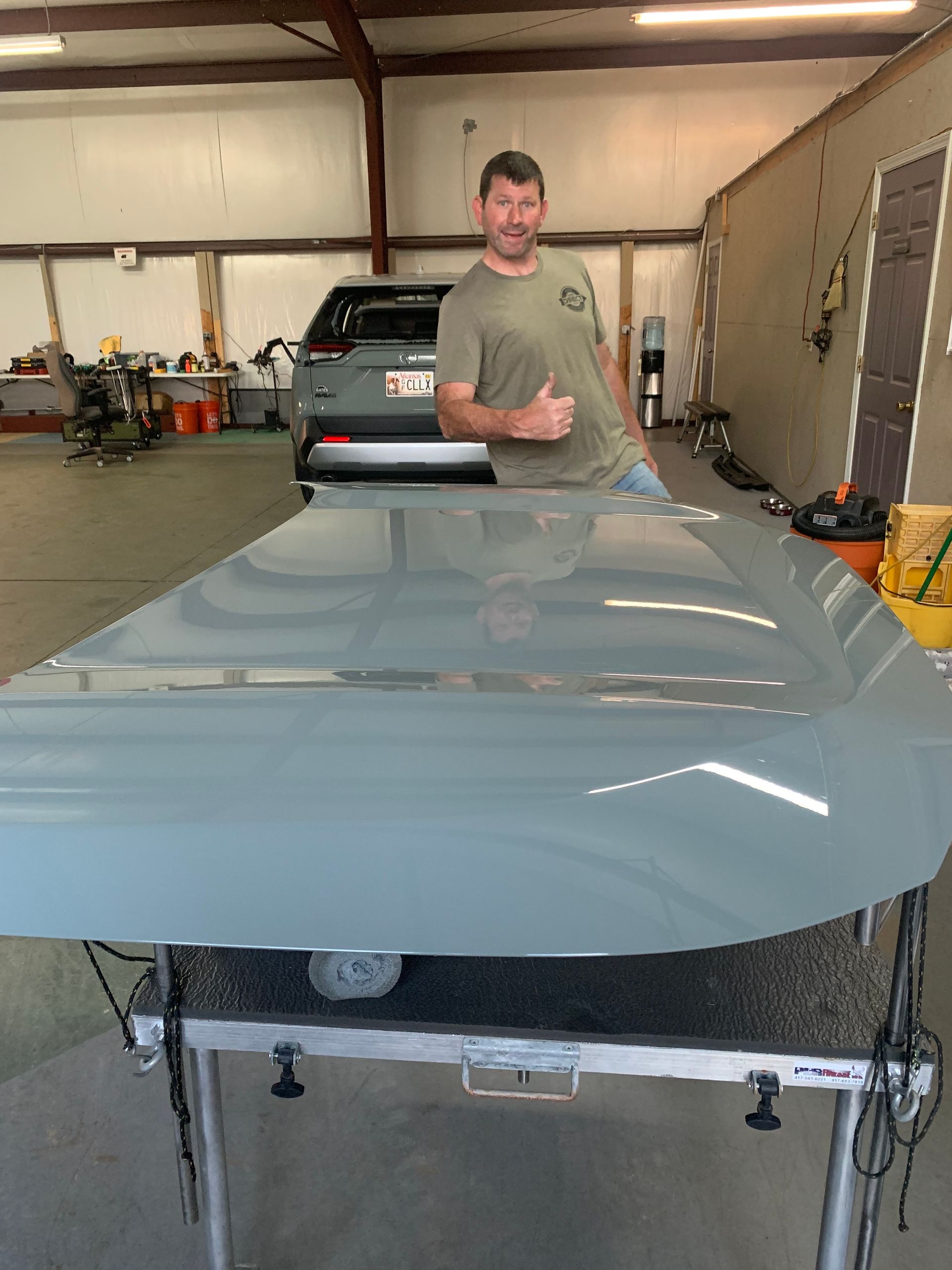 A man is standing next to a large piece of metal in a garage.