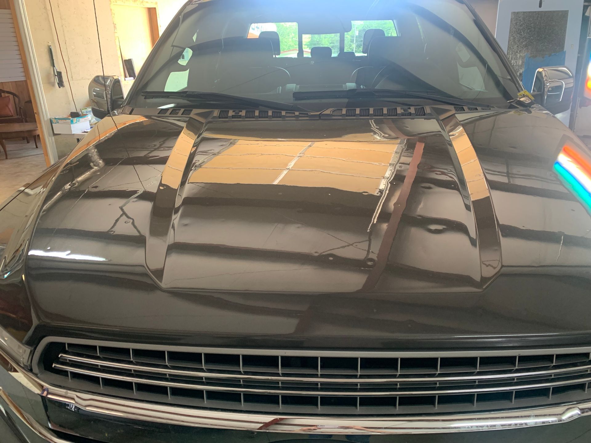 A black car is parked in a garage with a flag on the hood.