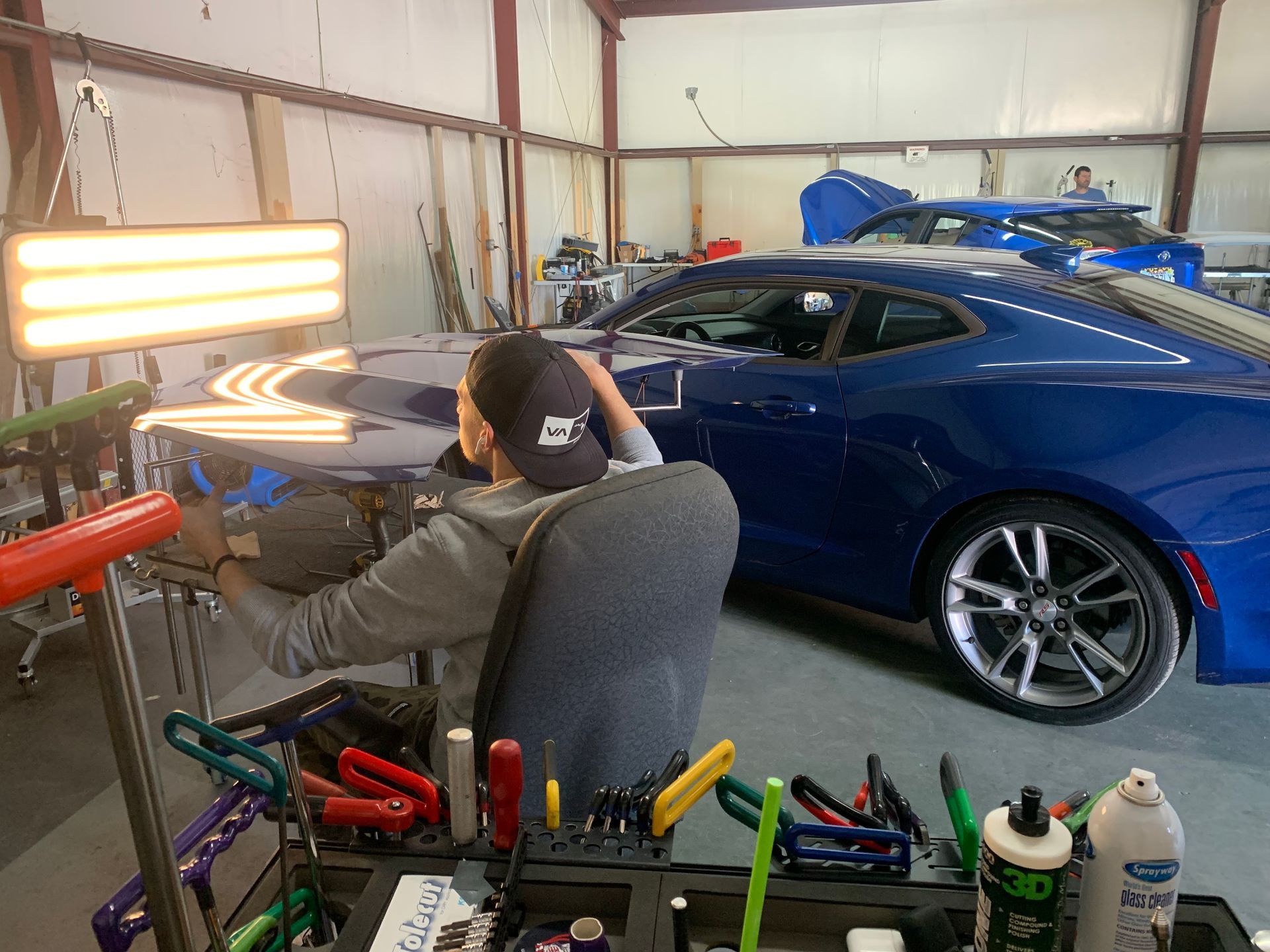 A man is working on a blue car in a garage.