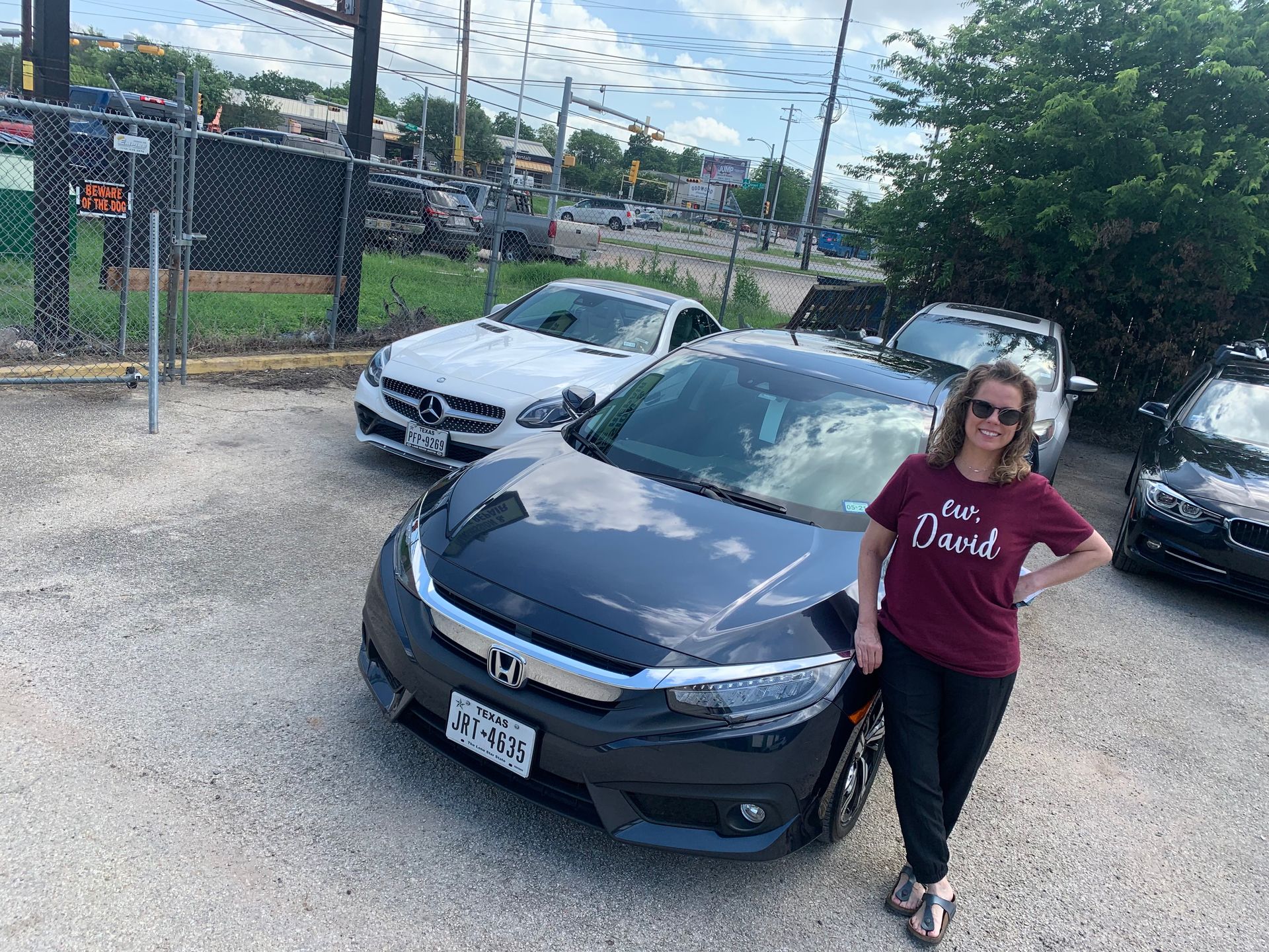 A woman is standing in front of a honda civic in a parking lot.