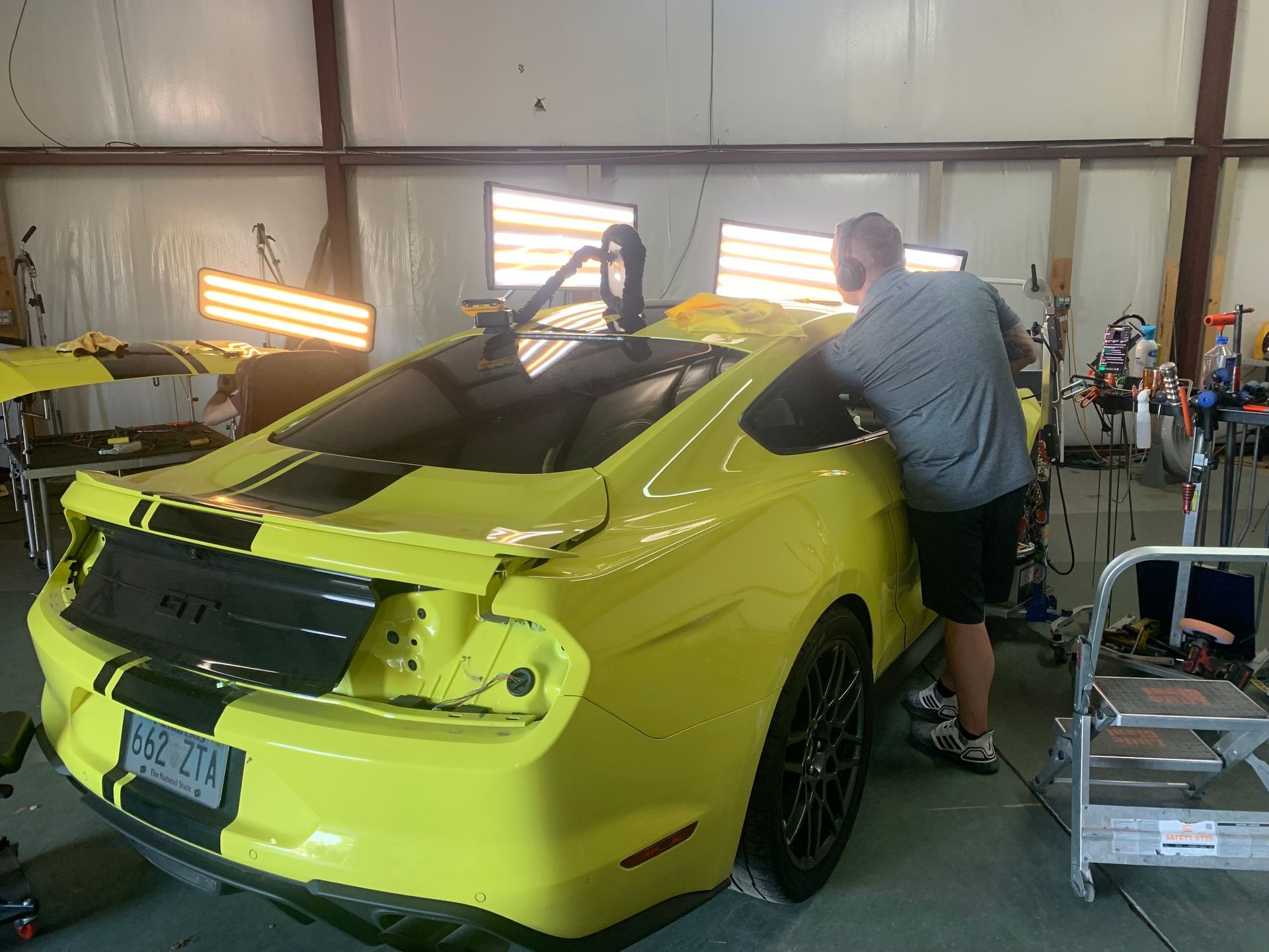A man is working on a yellow car in a garage.