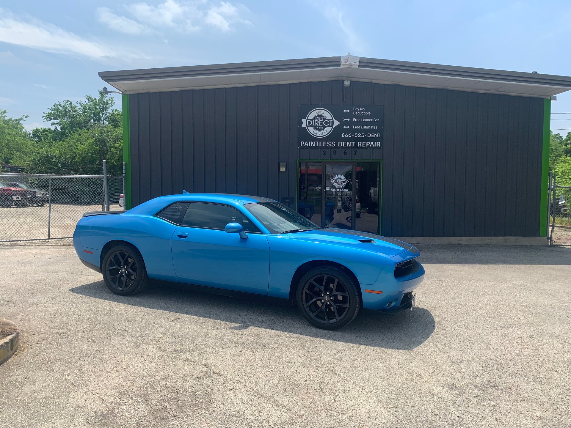A blue dodge challenger is parked in front of a building.