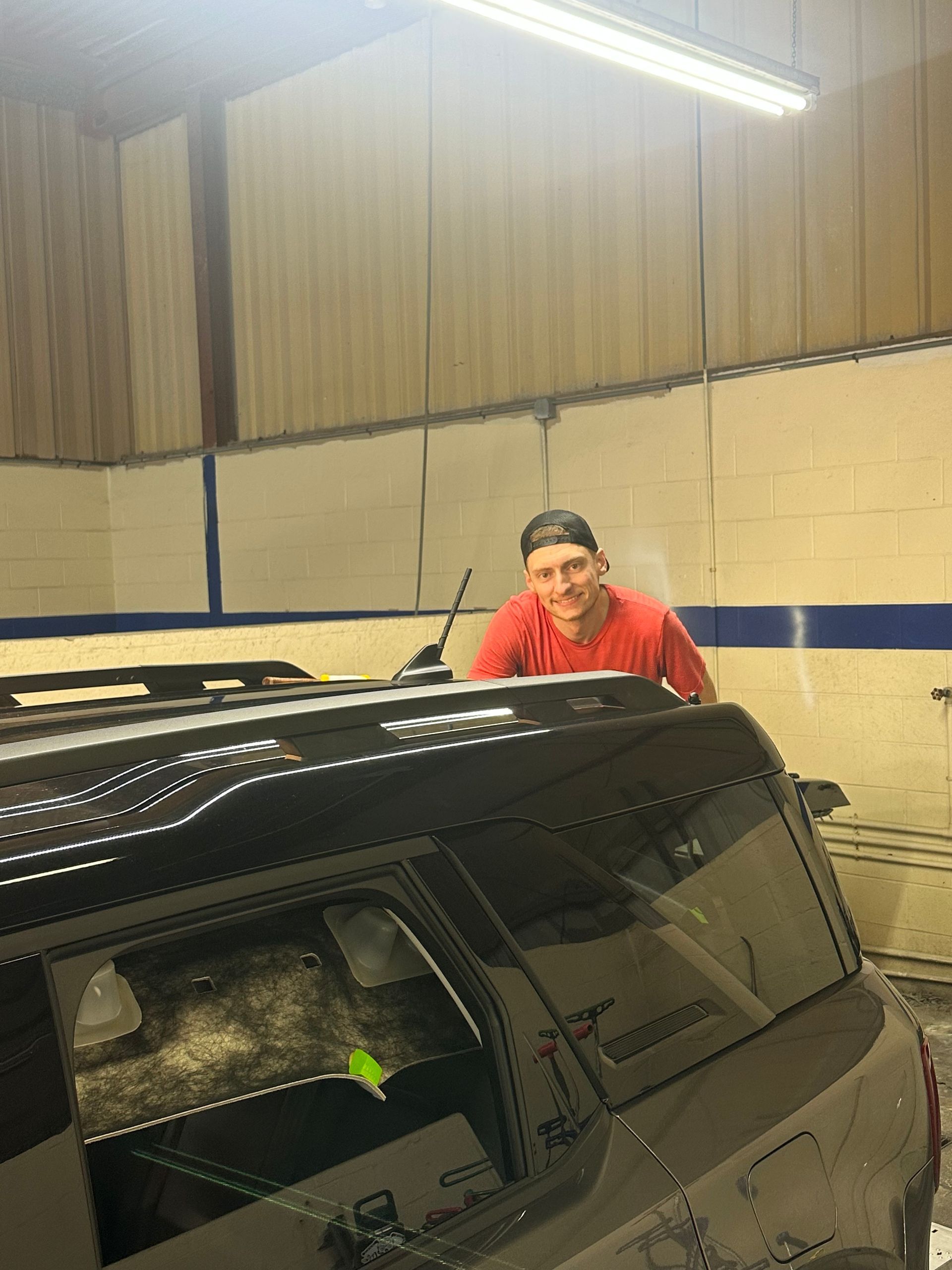 A man is standing on top of a car in a garage.