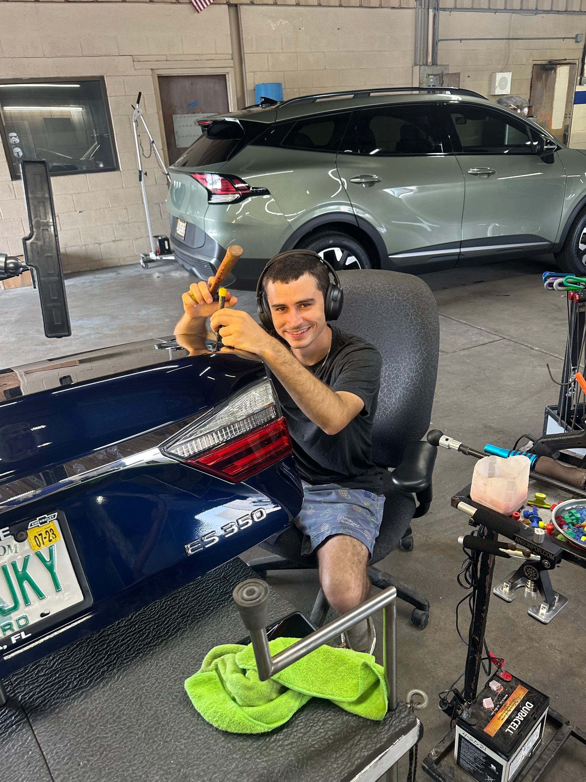 A man is sitting in a chair working on a car in a garage.