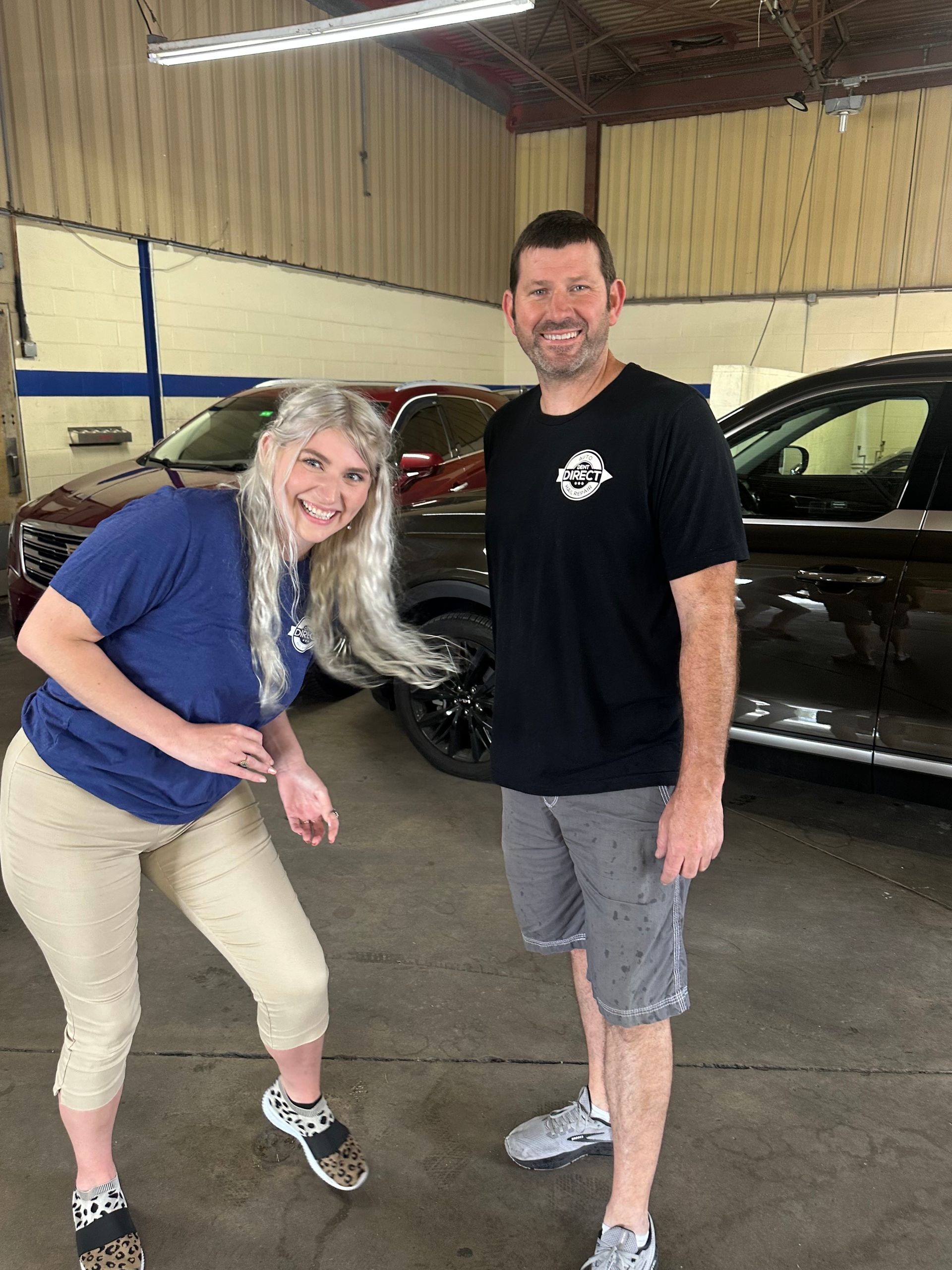 A man and a woman are standing next to each other in front of a car.