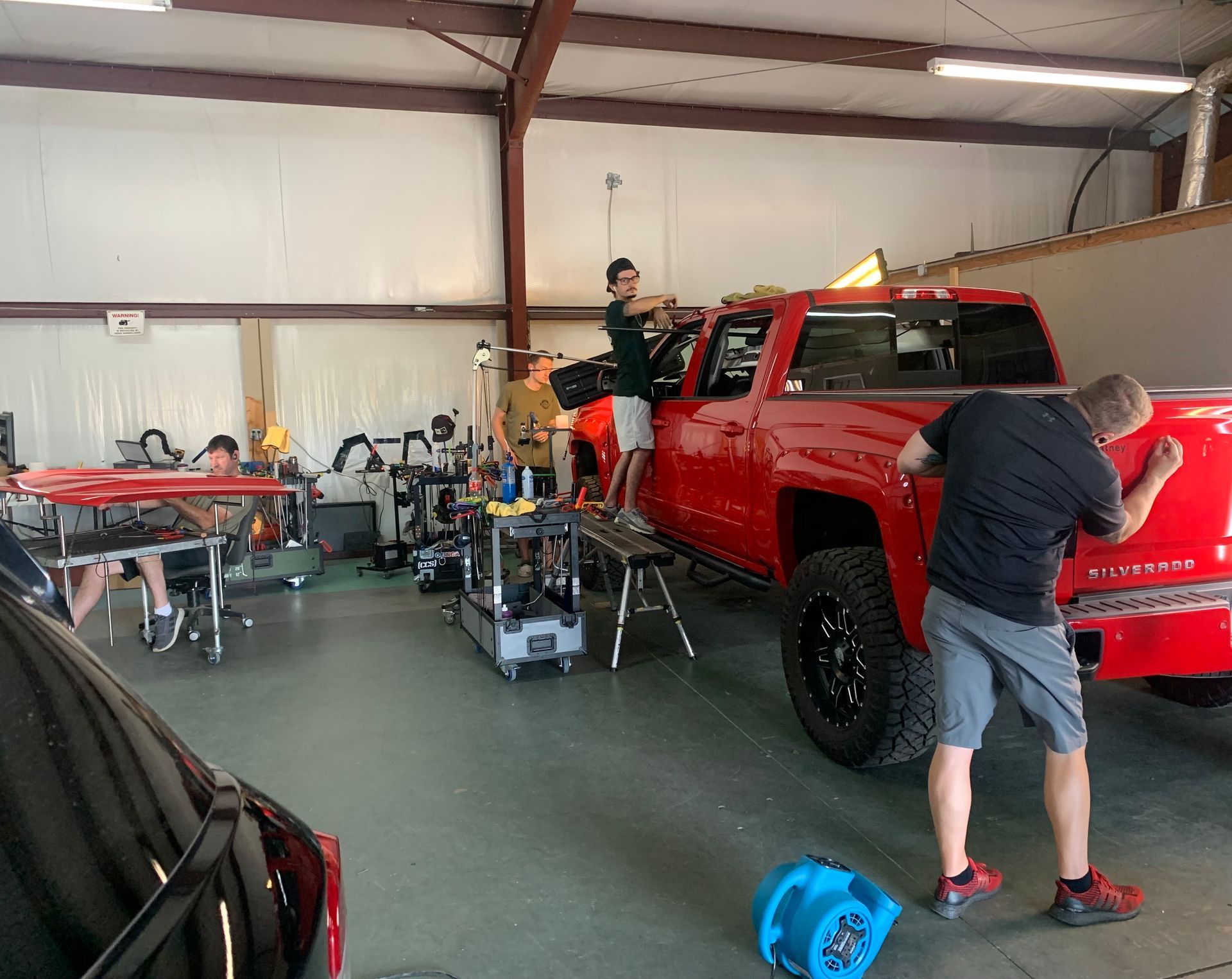 A man is working on a red truck in a garage.