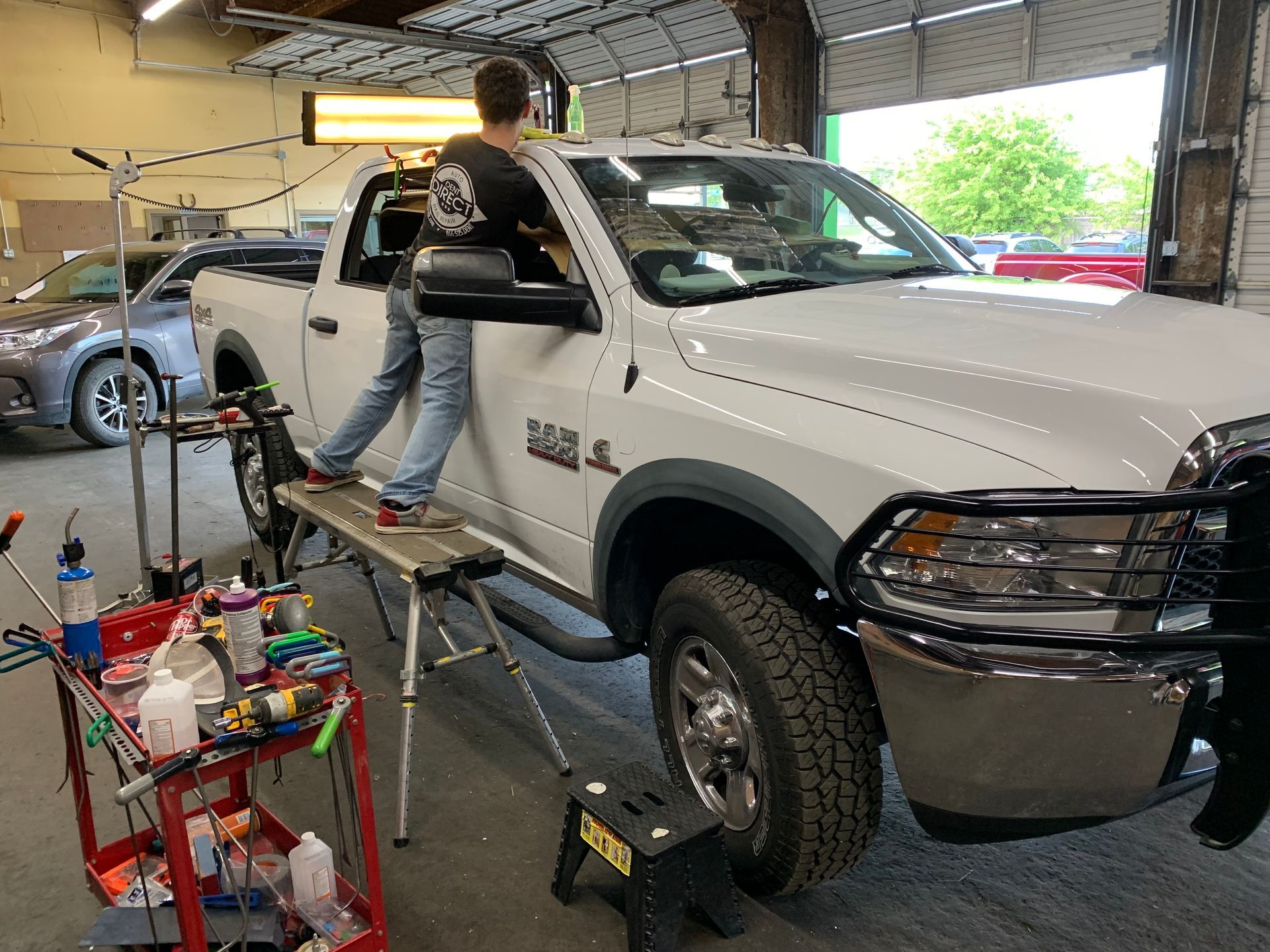 A man is working on a white truck in a garage.