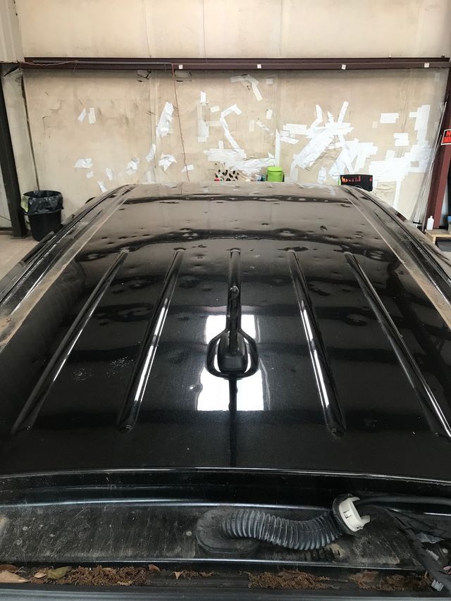 The roof of a black suv is sitting in a garage.