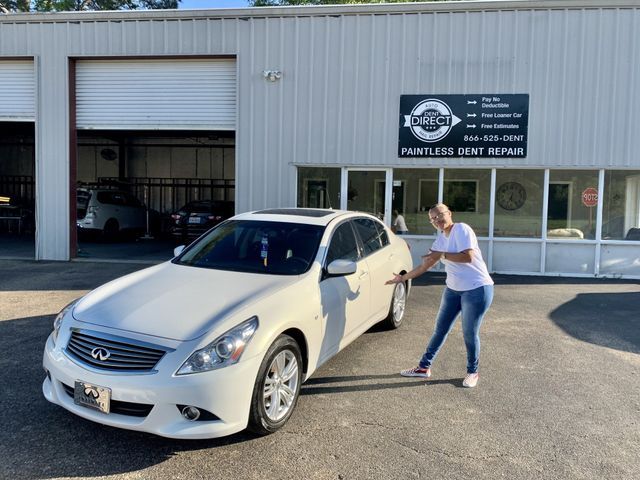 A woman is standing next to a white car in front of a building.