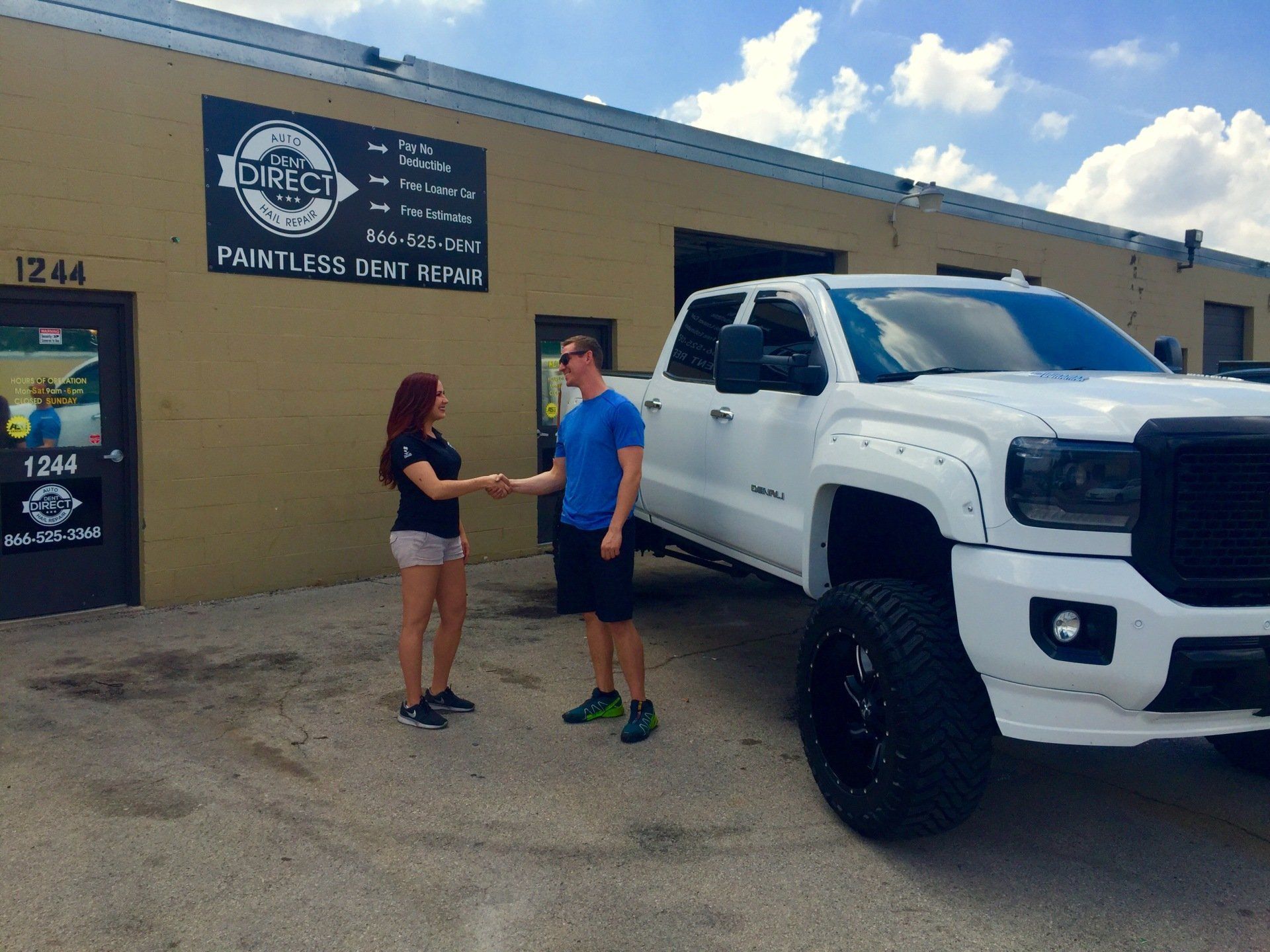 A man and woman shaking hands in front of a white truck