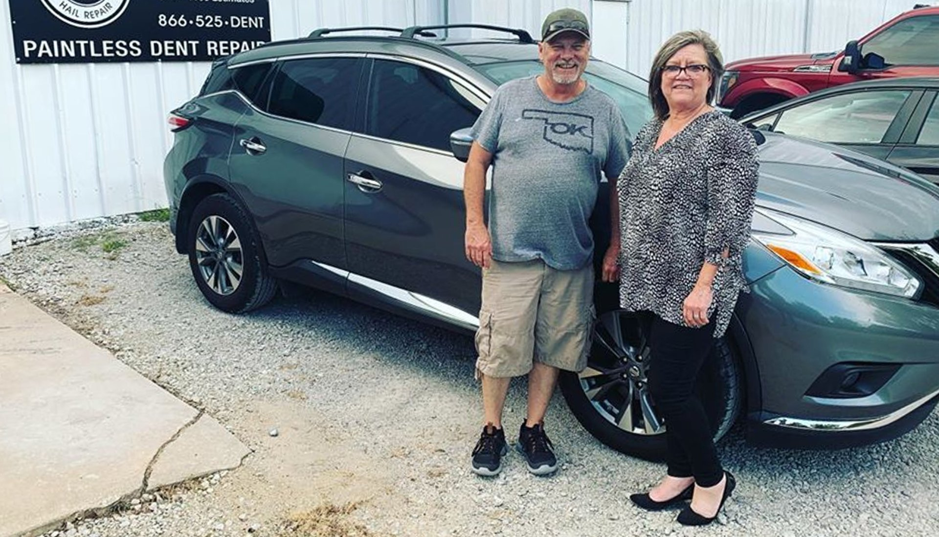 A man and a woman are standing in front of a car.