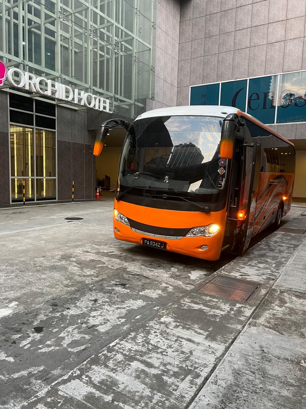 Orange tour bus parked at the Orchard Hotel entrance in Singapore.