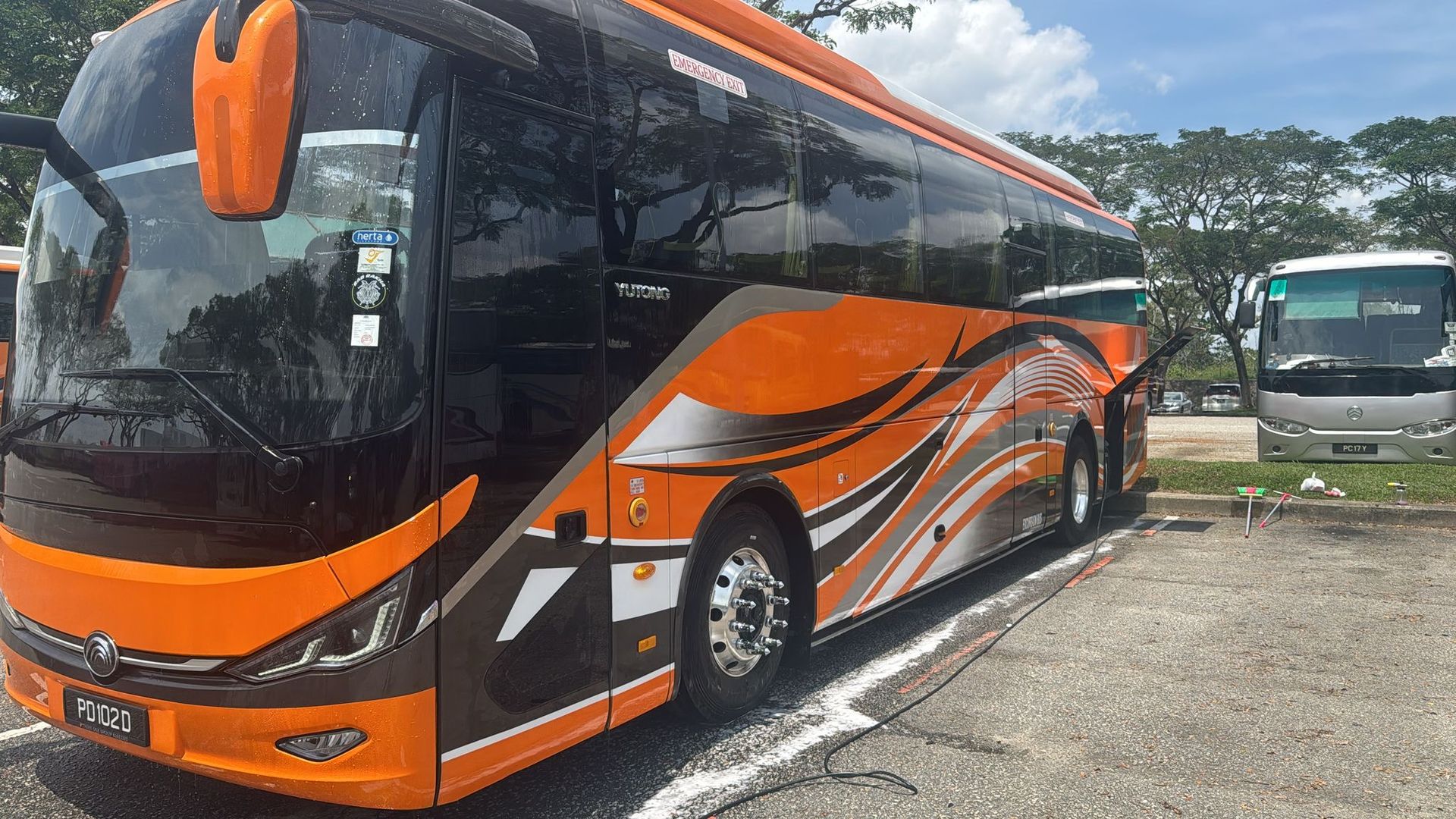 Orange and black coach bus parked in a lot under a cloudy sky