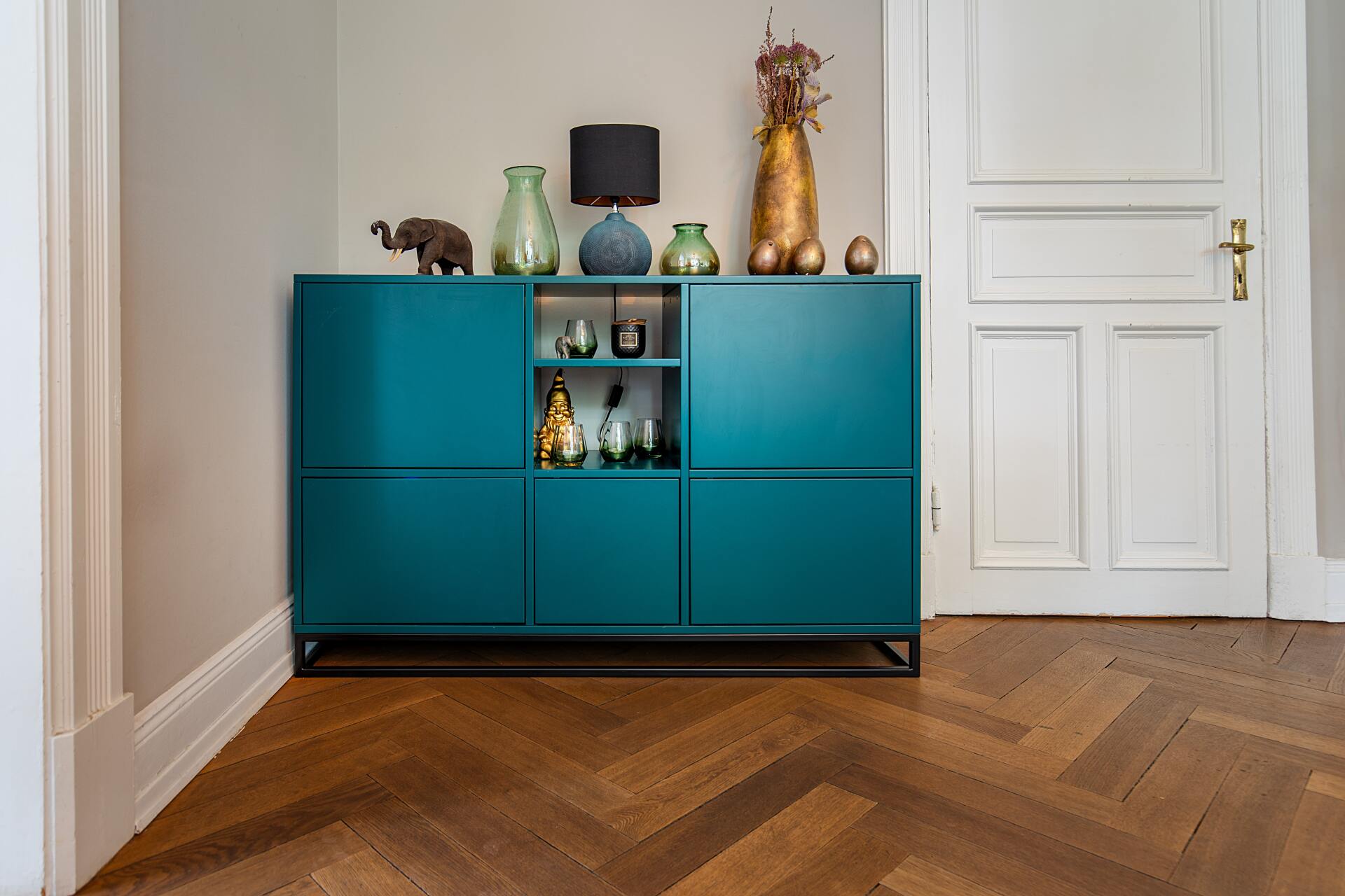 A blue dresser with vases and lamps on top of it