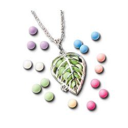 A necklace with a leaf shaped pendant is surrounded by candy.