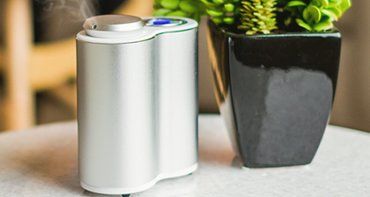 An essential oil diffuser is sitting on a table next to a potted plant.