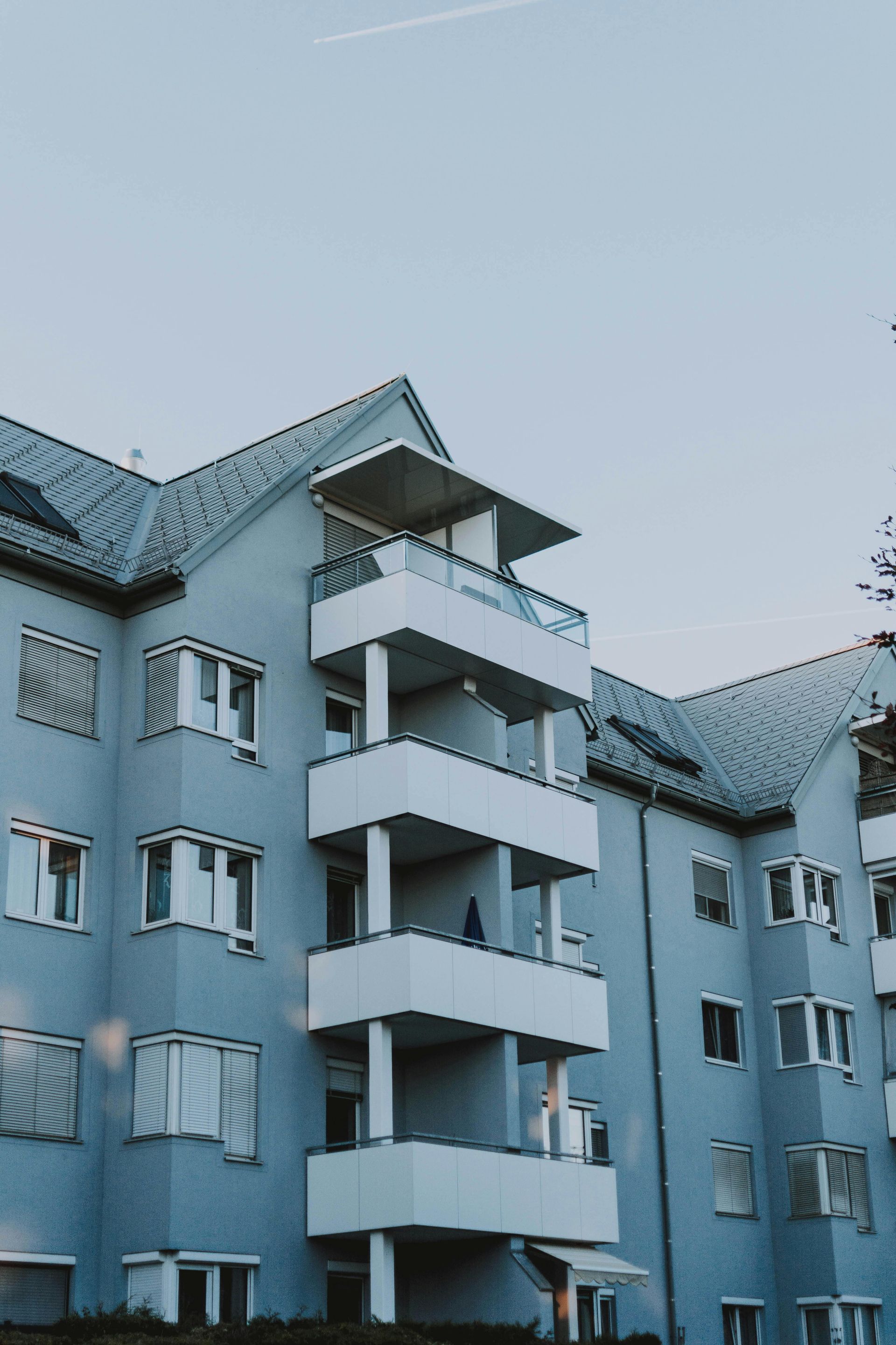 Blue apartment building with balconies against a dusky sky.