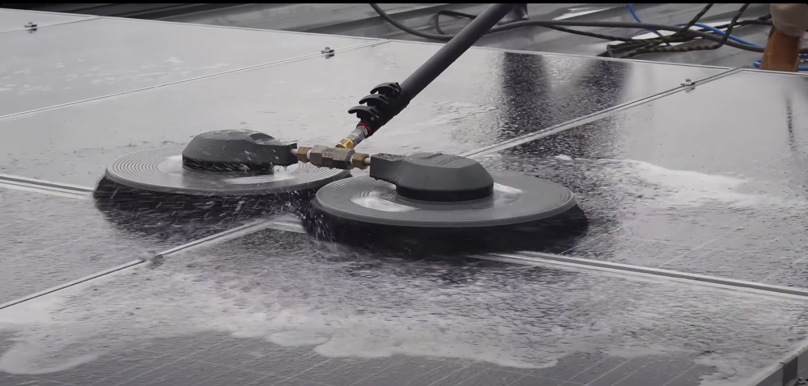 Two floor scrubber machines cleaning a wet surface on a rooftop or deck
